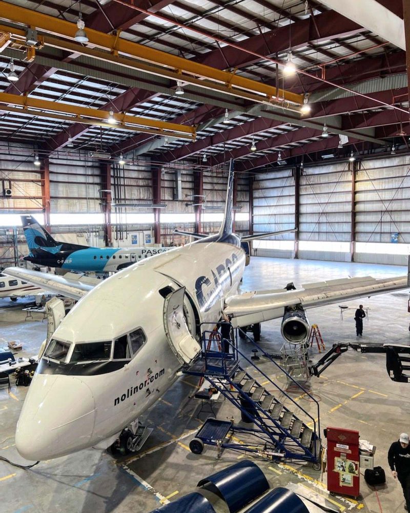 Avion cargo Nolinor en maintenance à l’intérieur d’un hangar, avec escabeau d’accès déployé et personnel technique au sol